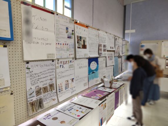 小学生の自由研究展の展示会場の様子。壁に作品が掲示され、見学者が作品を鑑賞している
